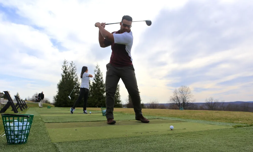 People practicing their swing at the driving range.