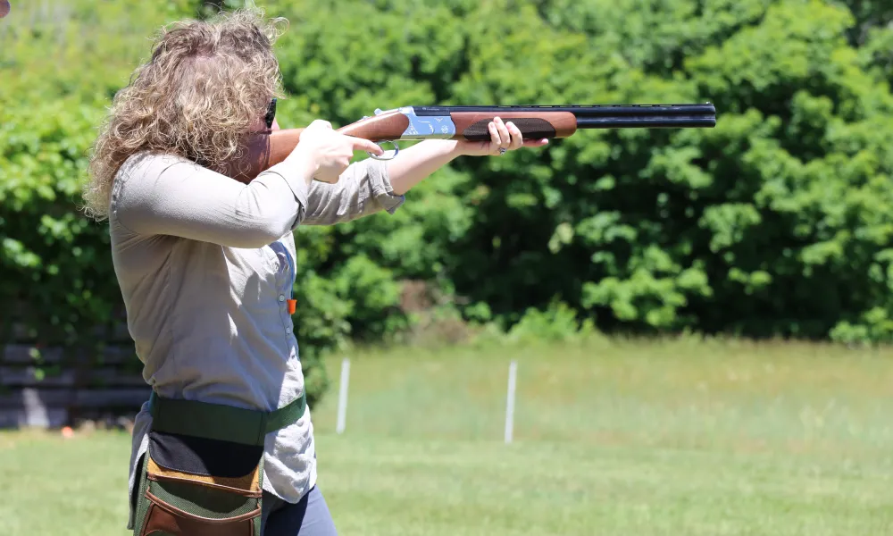 Woman shooting laser gun at clay targets.