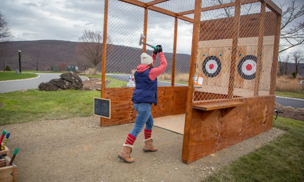 Woman throwing axe at target.