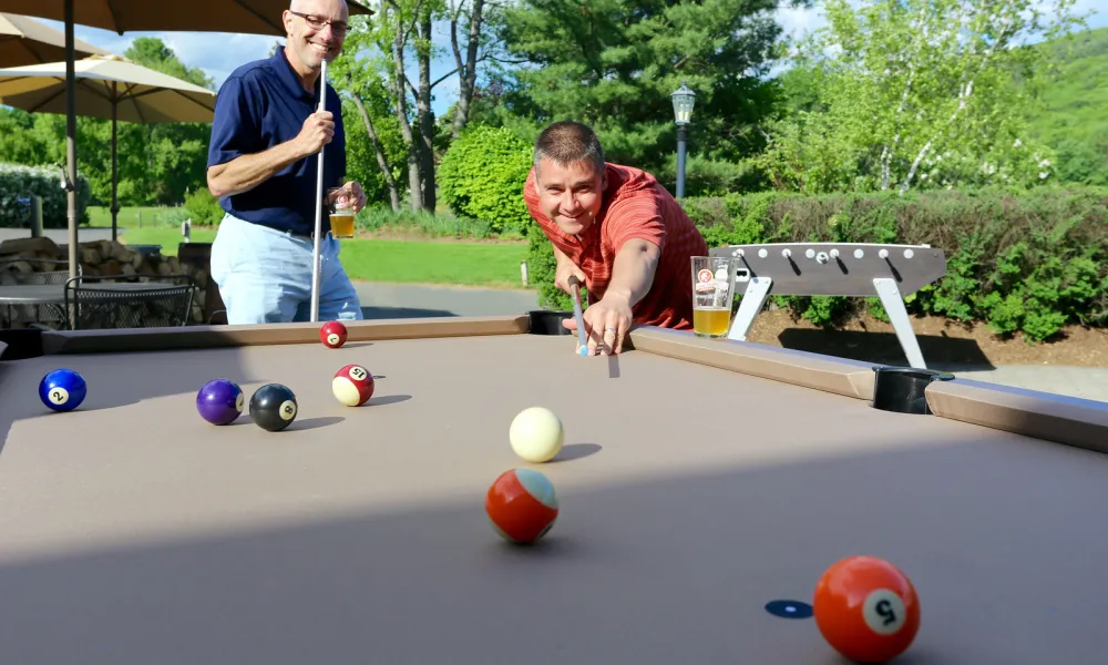 Couple of guys playing pool at the outdoor patio at Bear Den Grille