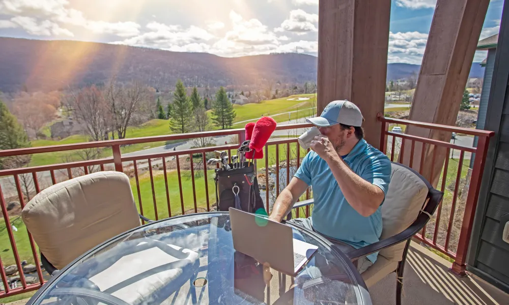 Man sitting on his balcony working on his laptop at Grand Cascades Lodge