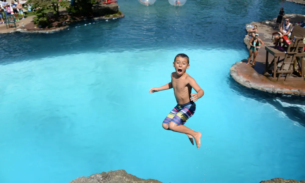 Young boy jumping off cliff at Minerals Hotel pool. 