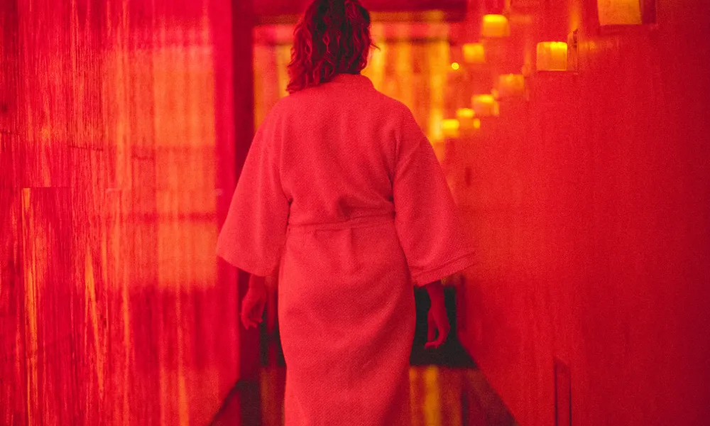 Woman in white robe walking down Reflections Spa hallway.