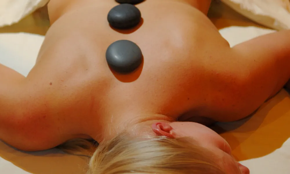 Woman laying with hot stones down the middle of her back.