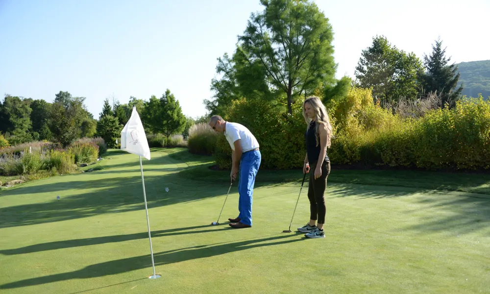 A couple playing mini golf on the natural putting green at Grand Cascades Lodge