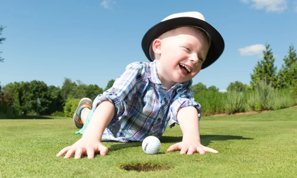 Boy smiling and laying on a golf course