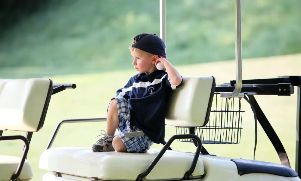 Young boy sitting in the back of a golf cart