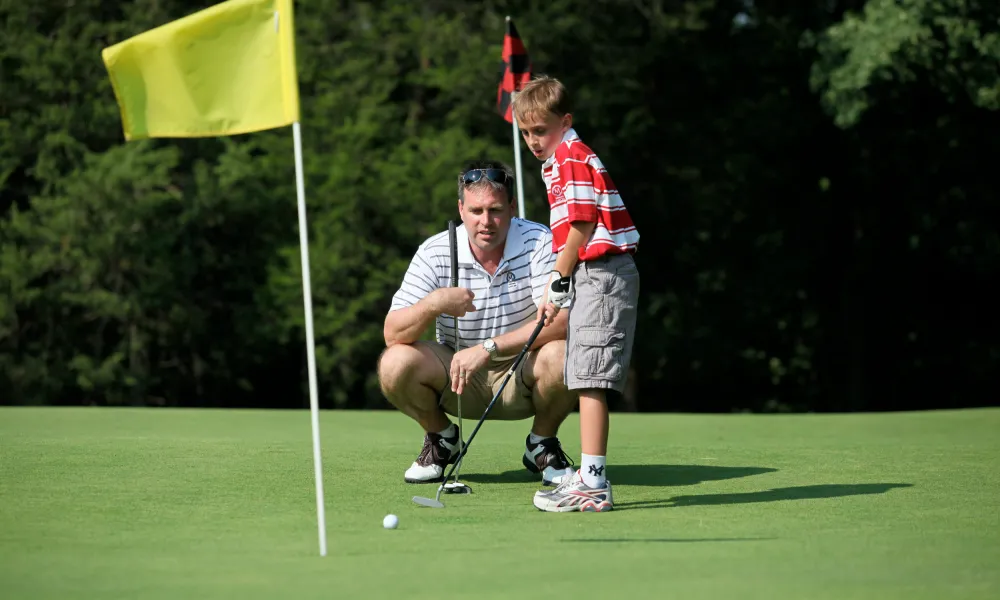 Father teaching his young son to golf at a resort near NYC