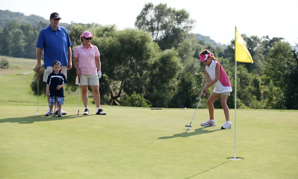 Young girl and family on the putting green on a course at Crystal Springs Resort