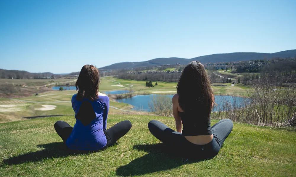 Two women practicing yoga at an overlook