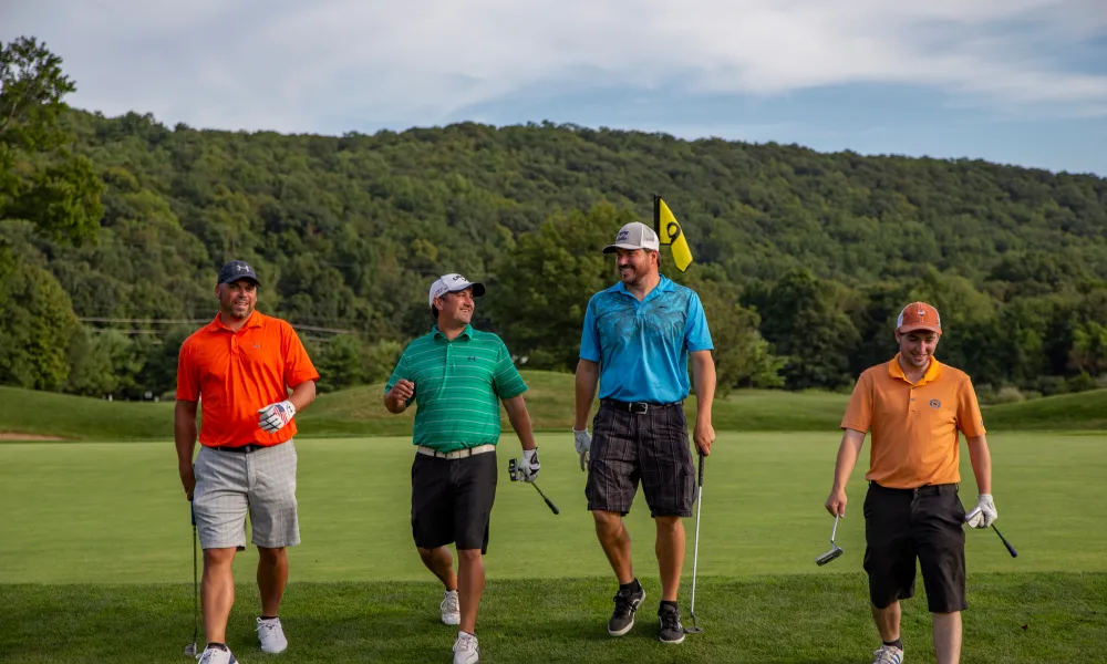 Four guys wearing multi-colored shirts walking on a golf course at a resort close to NYC