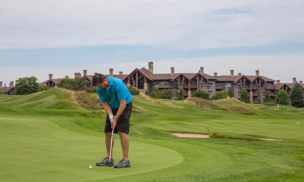 Man wearing a blue shirt putting on a green at the Crystal Springs Golf Course