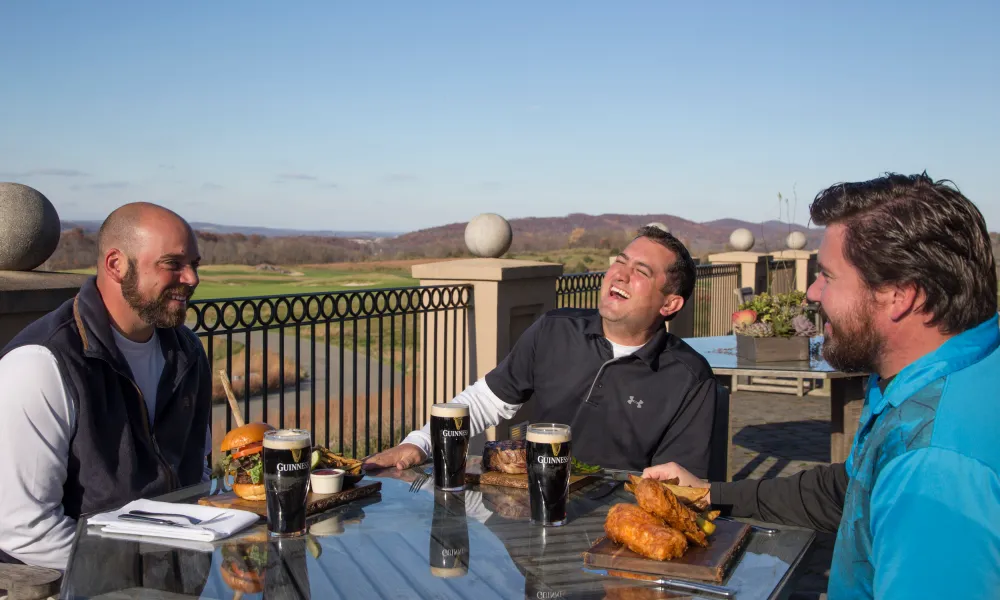 Men laughing and enjoying meals from Owen's Pub at Ballyowen Golf Club