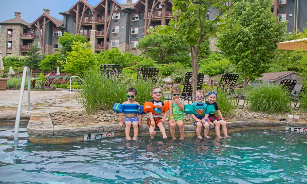 Children with floaties on sitting on edge of outdoor Biosphere pool.