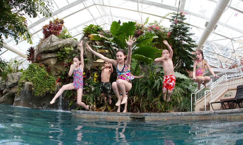 Group of children jumping into Biosphere pool complex.