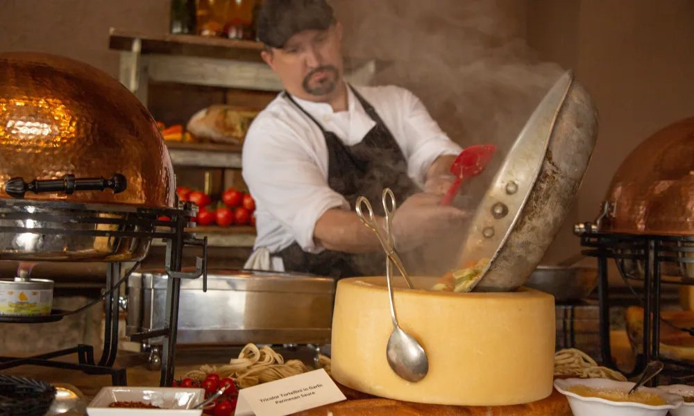 Chef making pasta in a cheese wheel