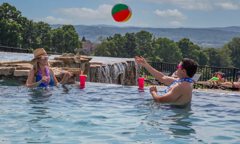 Woman and man playing with beach ball in vista 180 pool.