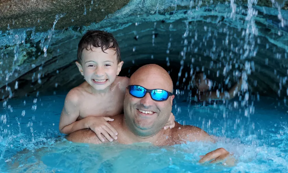 Father and Son under waterfall at minerals pool