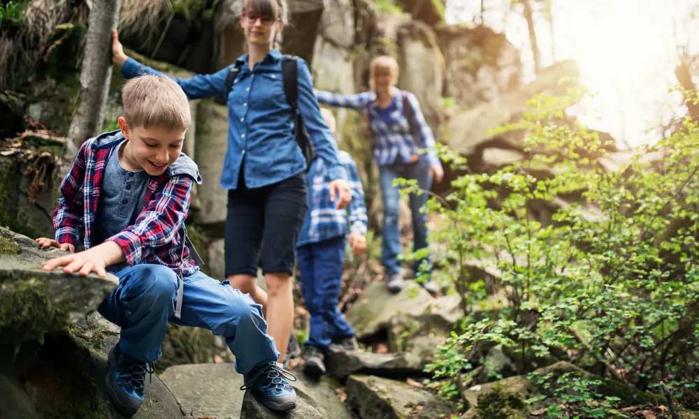 Kids crawling on rocks during family hike.