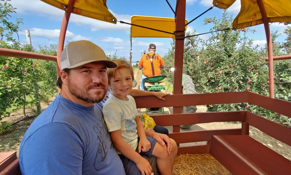 Family on tractor ride through apple orchard