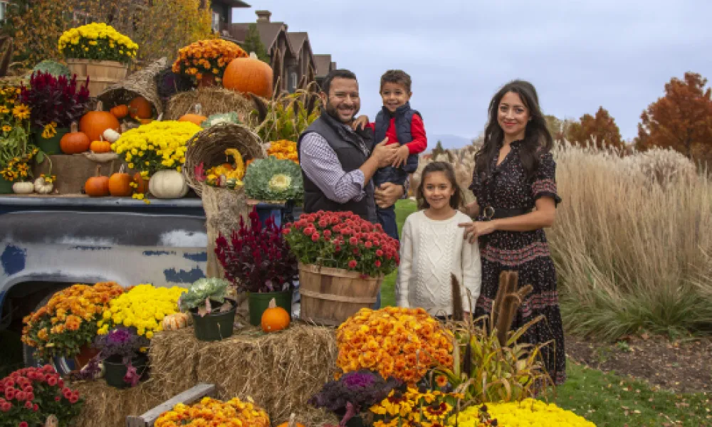 Family with fall mums in front of Grand Cascades Lodge