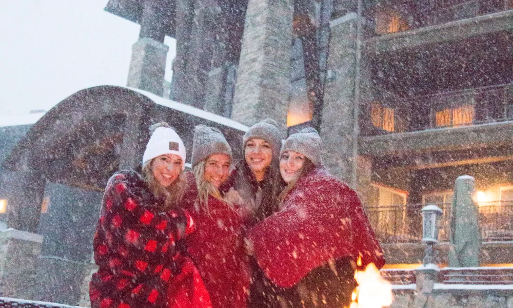 Four girlfriends standing around a firepit on the fire and water terrace at Grand Cascades Lodge NJ