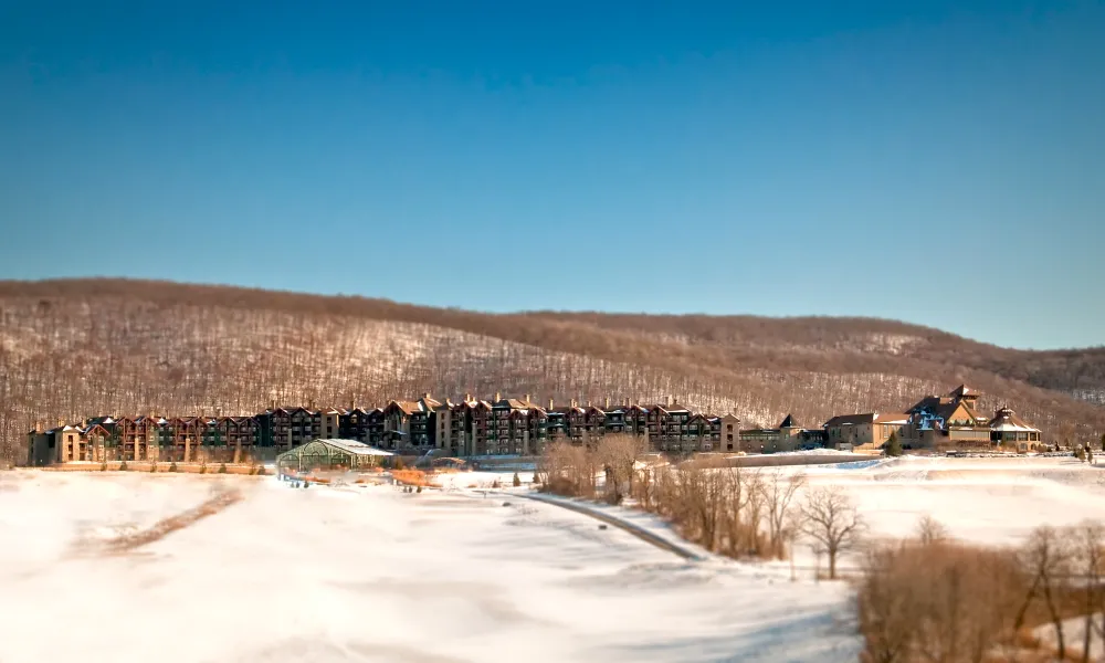 Distant view of Grand Cascades Lodge in front of the snowy mountains