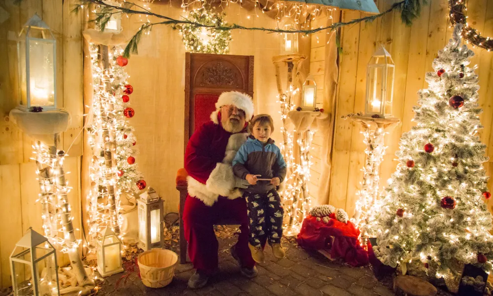 Boy sitting on Santa's lap in Christmas Corner at Grand Cascades Lodge. 