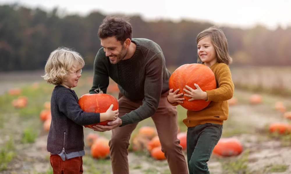 Two young children holding pumpkins.