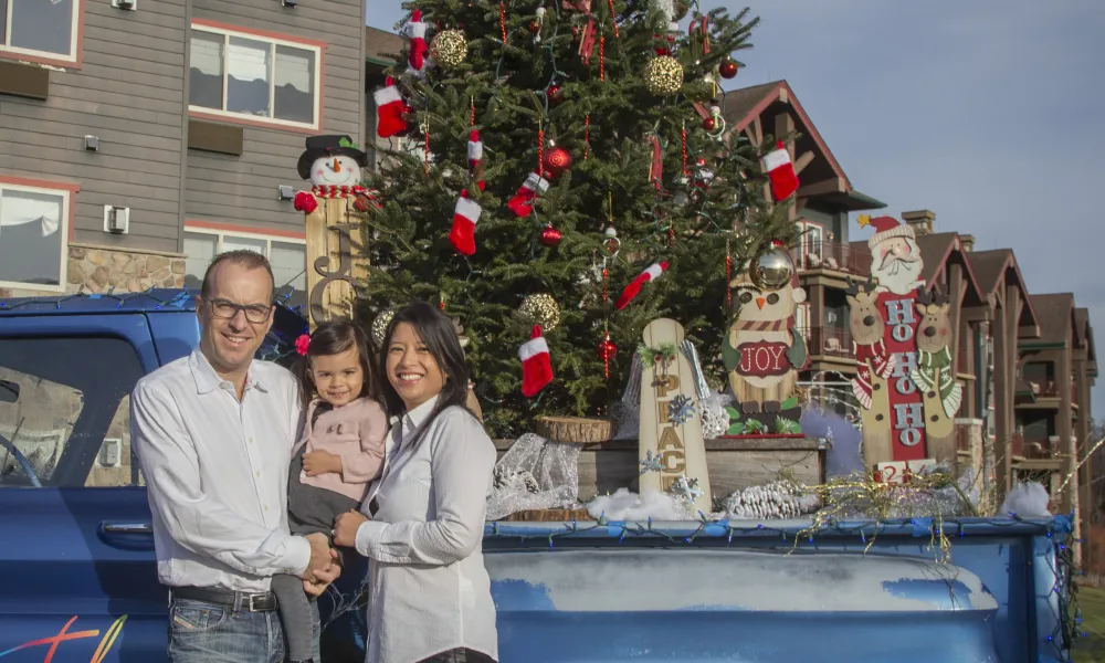 Parents and young daughter at decorative Christmas resort truck at Grand Cascades Lodge