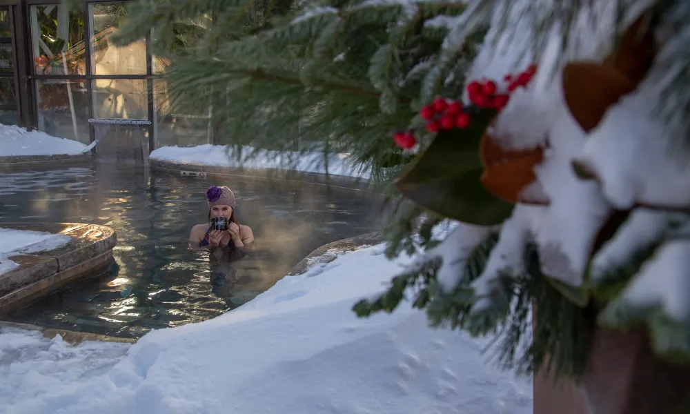 Woman drinking out of a mug in a snow pool.