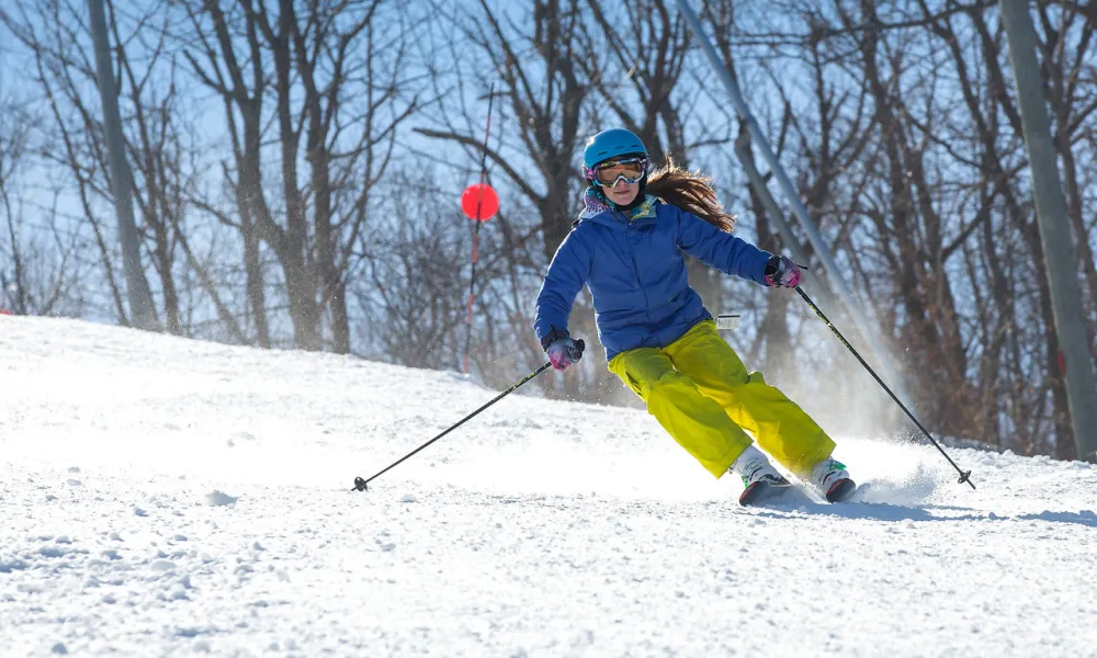 Person in blue jacket skiing down mountain.