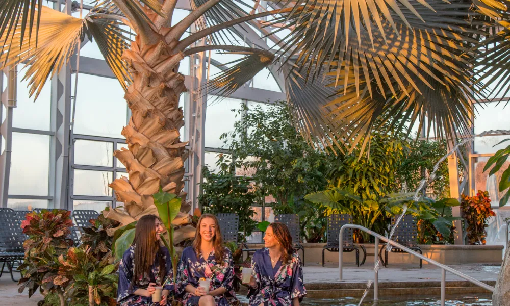 Women in robes sitting poolside at Biosphere pool complex