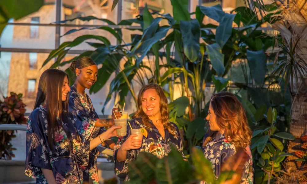 Four women in floral robes drinking in the Biosphere during girlfriends getaway.