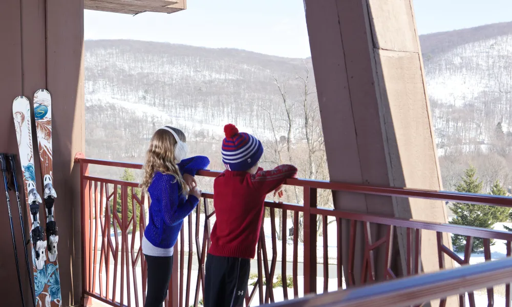 Children overlooking the snowy mountain view from balcony at Grand Cascades Lodge 