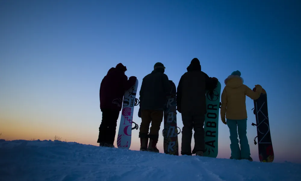 Group of snowboarders looking at sunset.