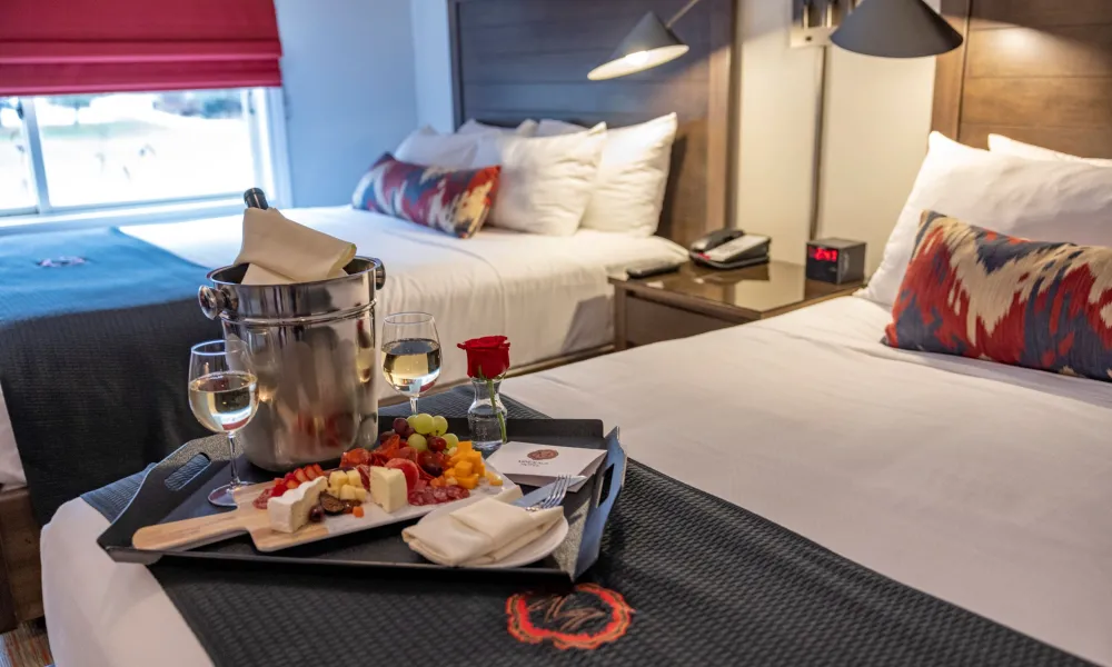 Wine and charcuterie board set on guest bed in deluxe room at Minerals Hotel