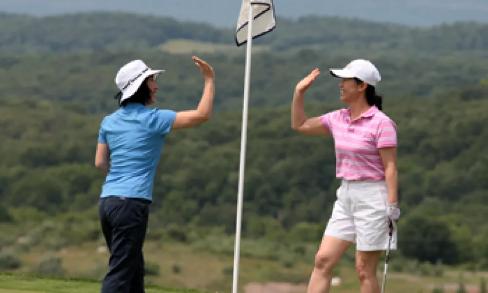 Two women high-fiving after a golf round