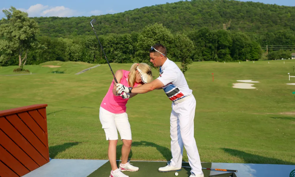 Golf instructor teaching a women to golf