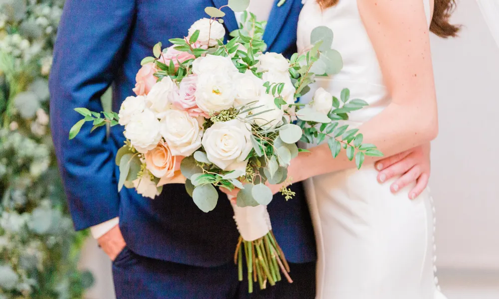 Bride and groom holding flower bouquet