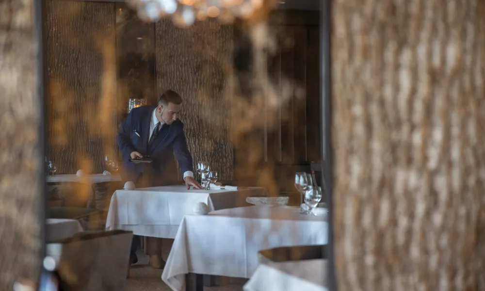 Waiter setting Restaurant Latour tables.