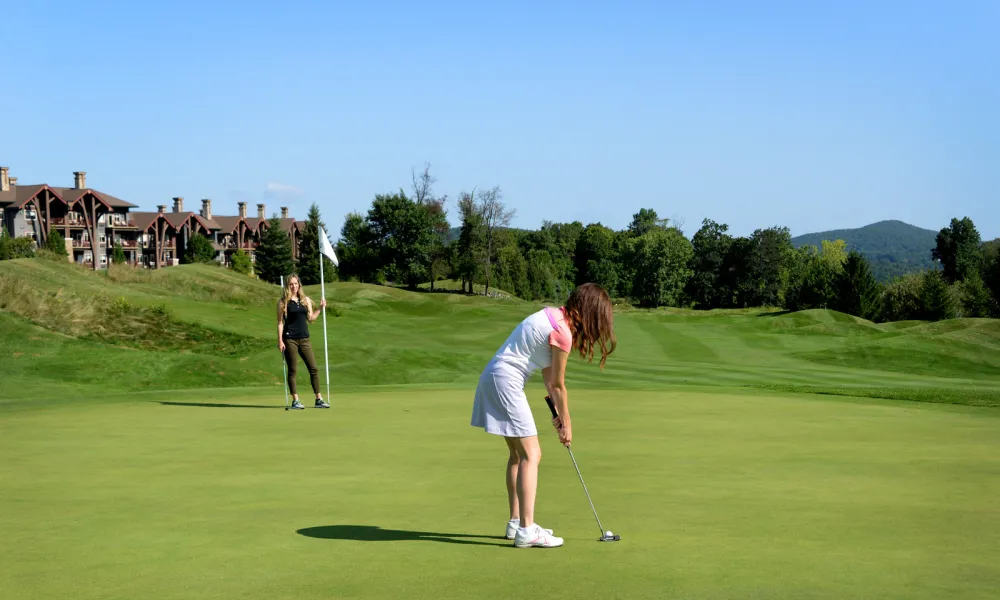 Two women on the green near a hole on a golf course