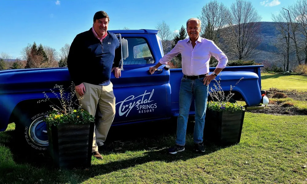 Kelsey Grammer and Chris Mulvihill standing by blue truck.