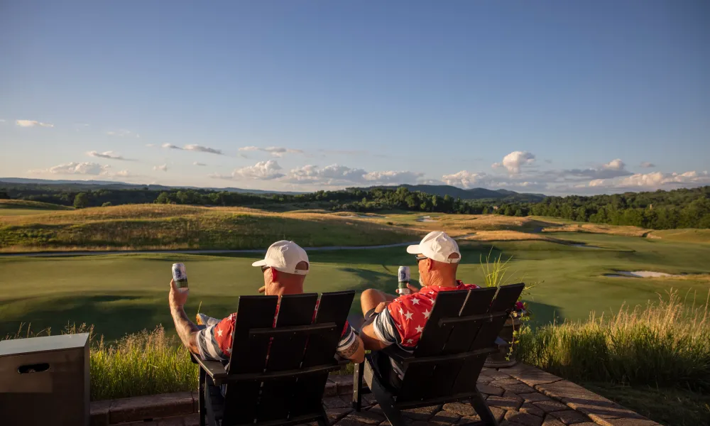 Two golfers sitting in adirondack chairs at sunset on the Ballyowen Golf Course