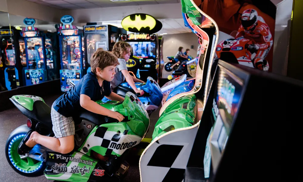 Young boy on motorcycle arcade game.