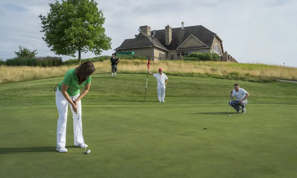 Women putting on the greens of Ballyowen with bagpiper playing on the side