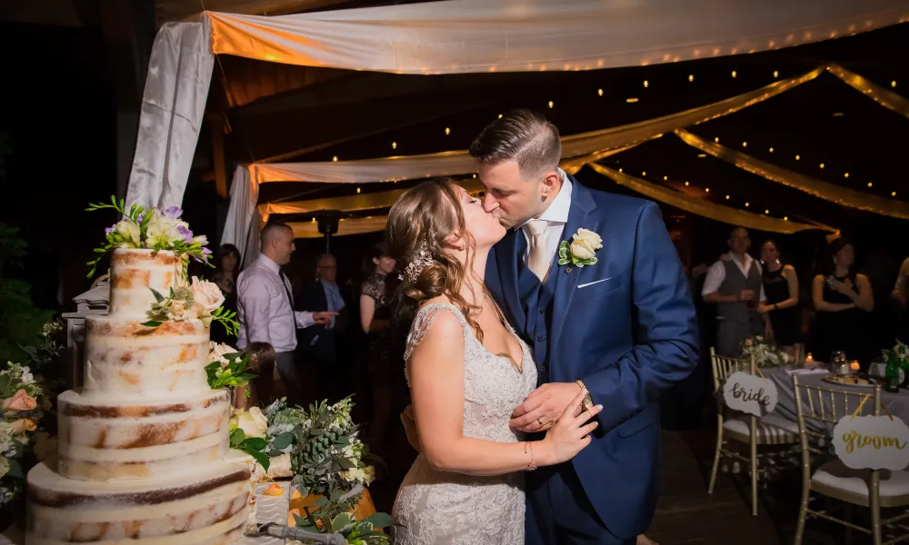 Bride and Groom kissing next to the wedding cake