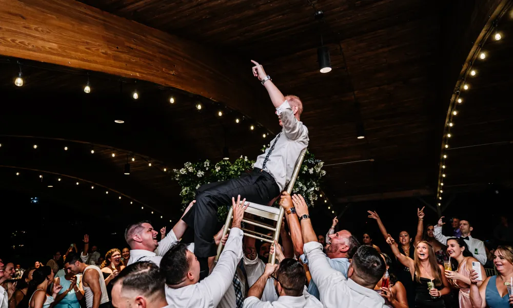 Groom raised on chair during wedding reception in Sweetgrass Pavilion