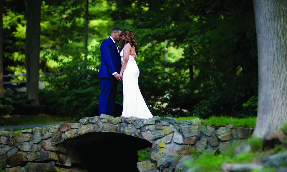 Bride and groom standing over bridge holding hands