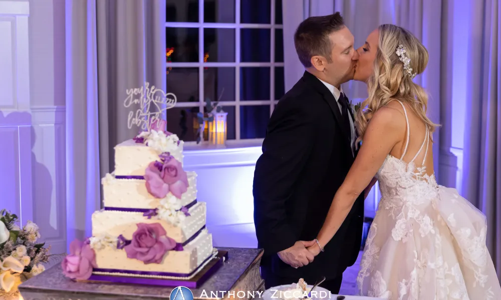 Bride and Groom kissing by wedding cake